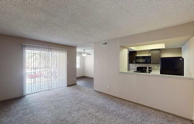 A spacious living room with a sliding glass door leading to a balcony.