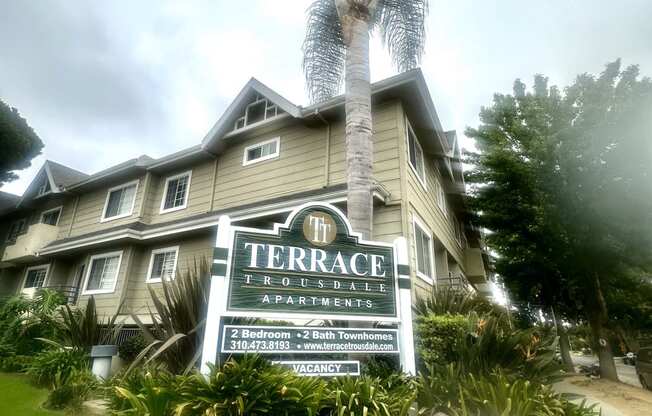 a building with a sign in front of a palm tree