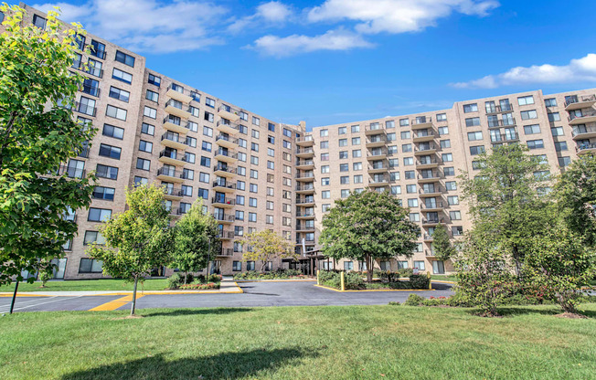 a view of a large apartment complex with grass and trees