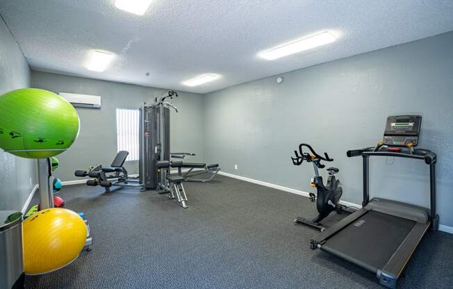a gym with exercise equipment and a green ball in the corner