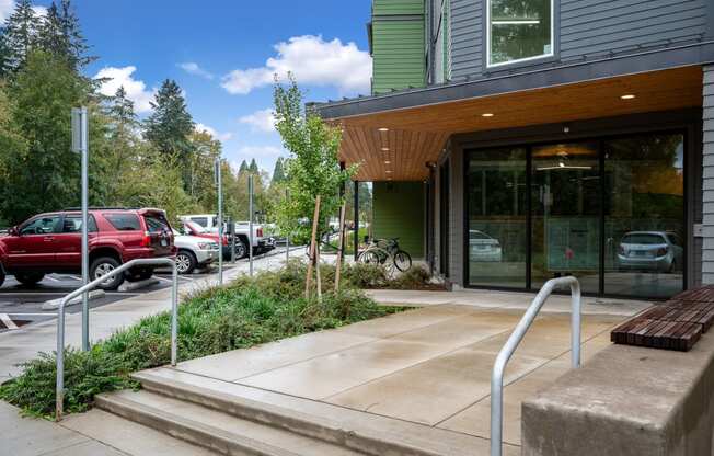 a building with stairs and a sidewalk in front of a parking lot