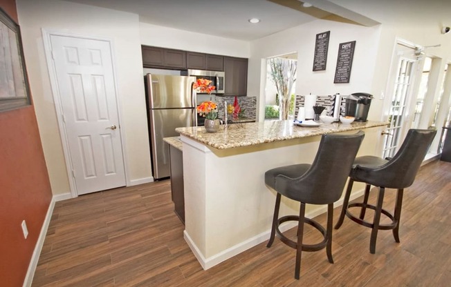 a kitchen with a breakfast bar and a stainless steel refrigerator