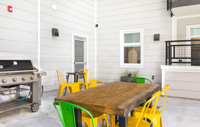 a patio with a table and chairs and a grill