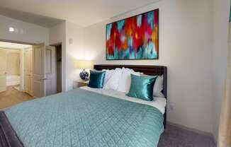 a bedroom with a large bed and a colorful painting on the wall