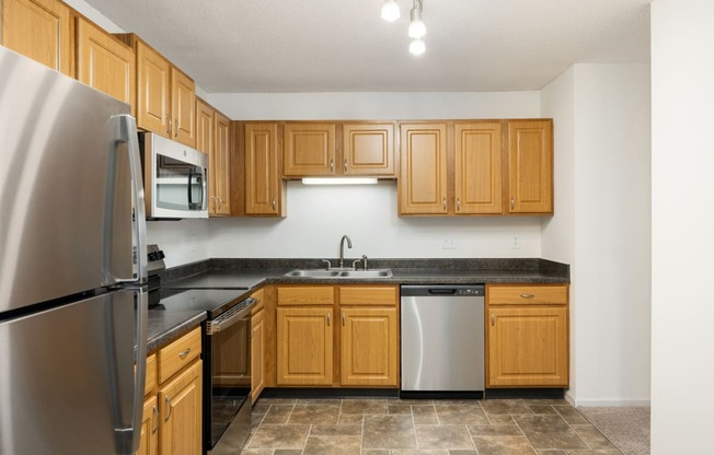 an empty kitchen with wooden cabinets and stainless steel appliances