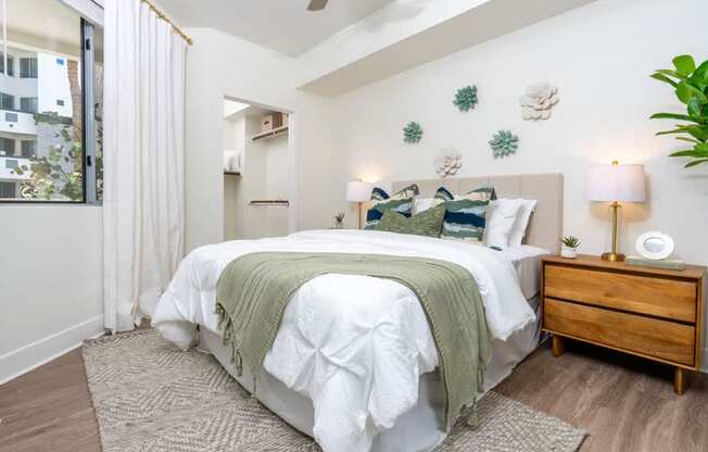 A bedroom with a large bed, a nightstand, and a ceiling fan.