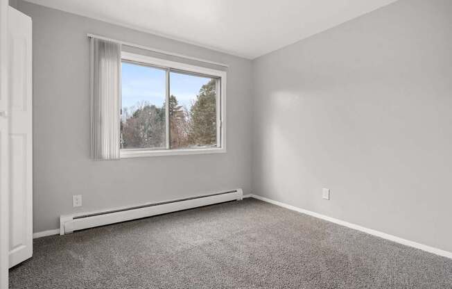 A room with a window and a carpeted floor.