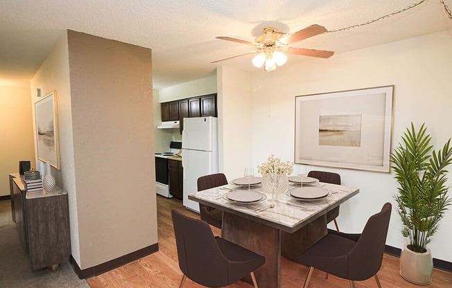 a dining area with a table and chairs and a kitchen in the background