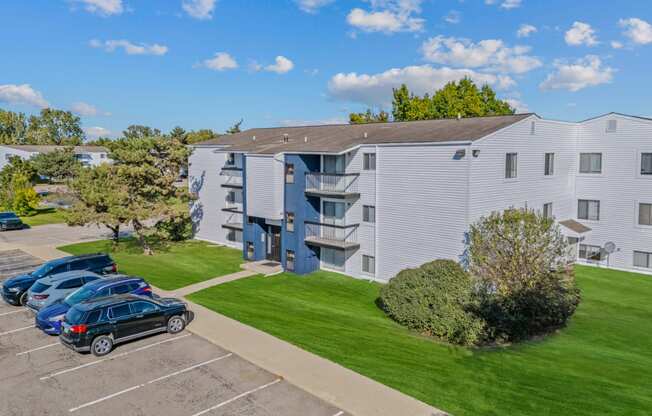 the view of an apartment building with cars parked in front of it