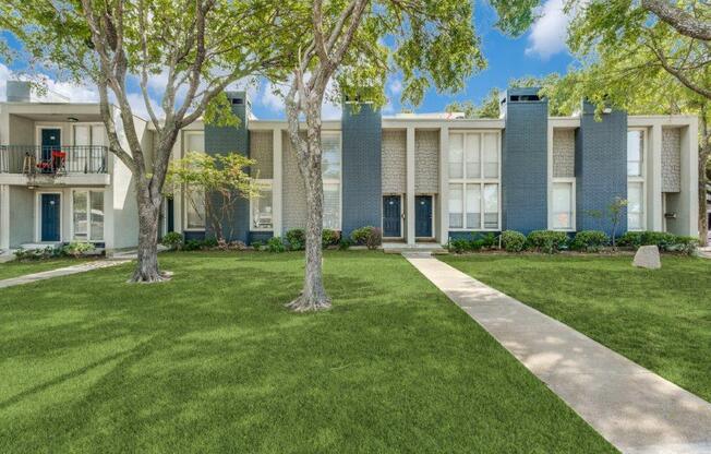 an apartment building with grass and trees in front of it