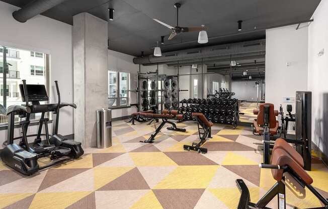 A gym with a variety of equipment including treadmills, weights, and exercise machines.