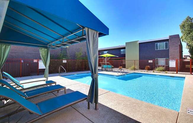 A pool area with a blue canopy and a green umbrella.