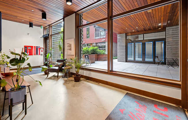 A room with a wooden ceiling and floor, and a large window with a view of the outside.