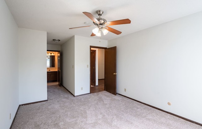 a bedroom with a ceiling fan and white walls. Eagan, MN Glen Pond Apartments