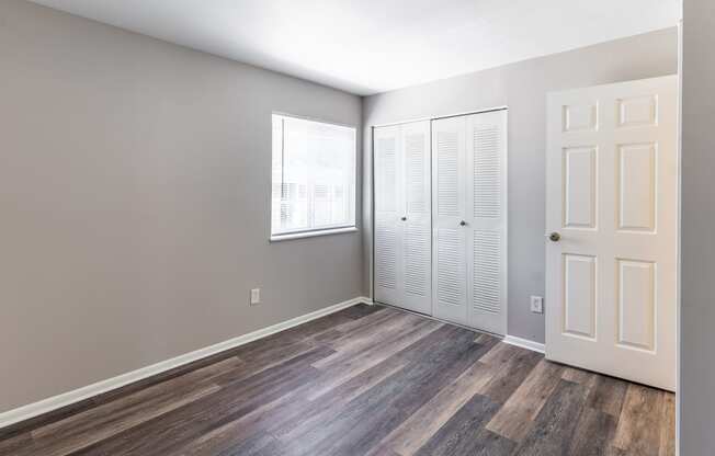an empty room with wood flooring and white closet doors