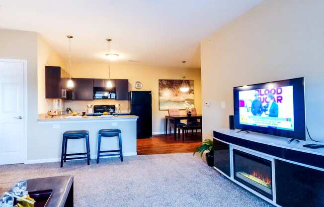 a living room with a flat screen tv and a kitchen in the background