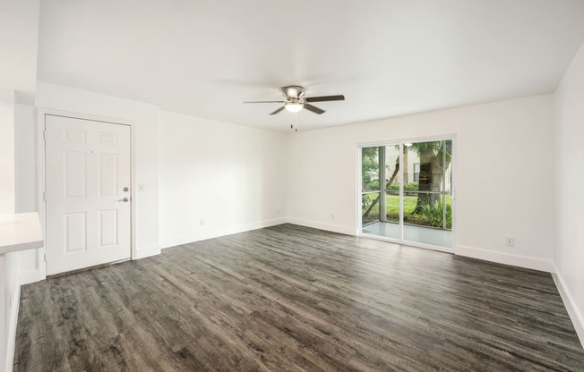 an empty living room with a ceiling fan and a window