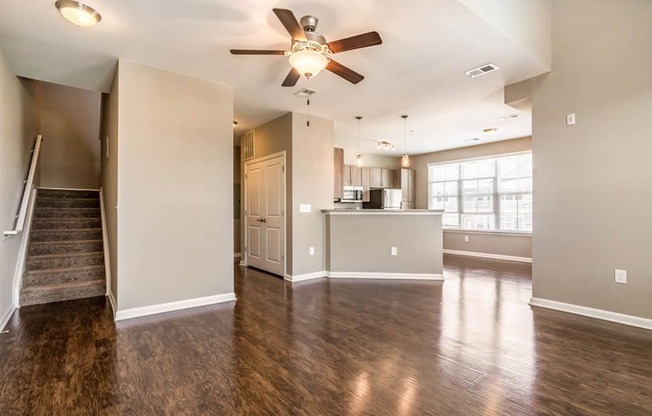 an empty living room and kitchen with a ceiling fan