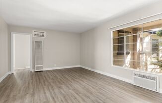 an empty living room with a large window and wood flooring