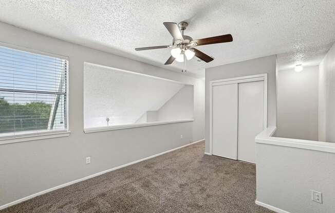 A room with a ceiling fan and carpeted floor.