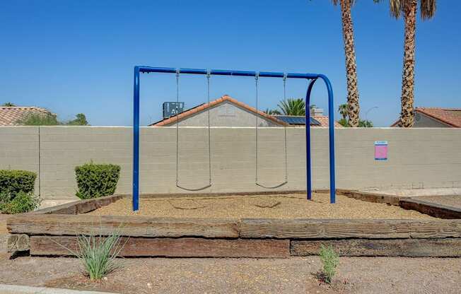 A playground swing set with a blue frame and a brown wooden slide.