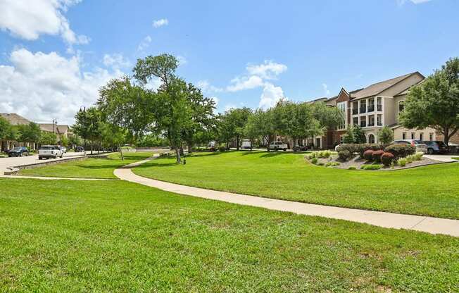 A green lawn with a white pathway and a building in the background.