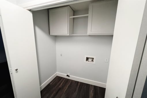 a room with white cabinets and a white wall and wood floors