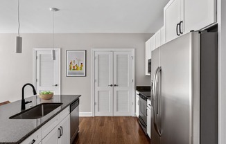 A modern kitchen with a stainless steel refrigerator and wooden floors.