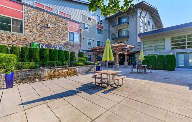 a patio with tables and umbrellas outside of an apartment building at Delano, Redmond, WA 98052