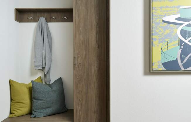 a hallway with a bench with pillows and a door to a closet