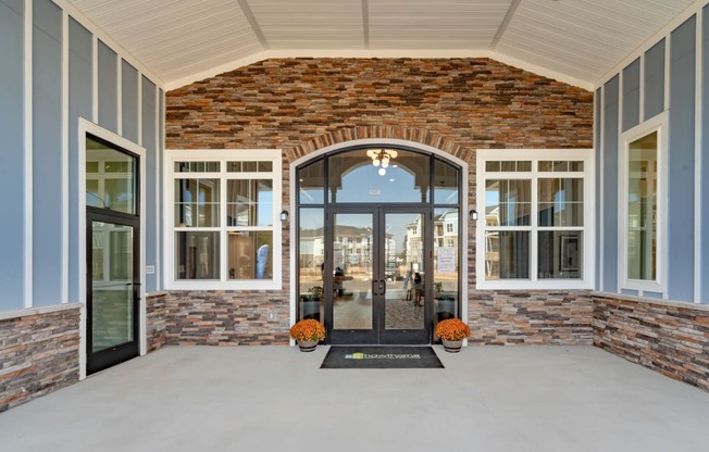 the view of the front porch of a brick building with glass doors