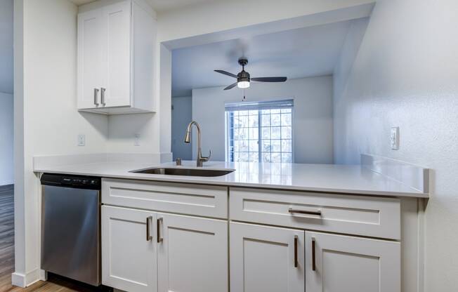 One-Bedroom Apartments in Everett, Washington - Woodbrook - Kitchen with Wood-Style Flooring, Stainless Steel Dishwasher, Sleek White Cabinets, and Breakfast Bar.