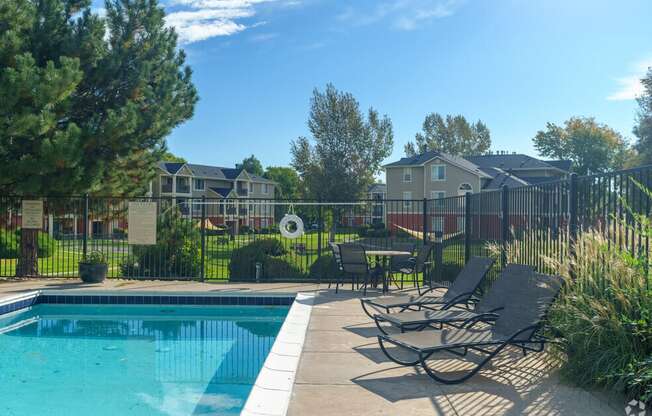 a swimming pool with lounge chairs next to a fence