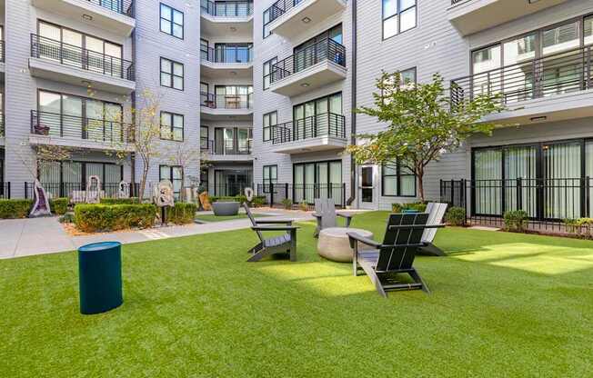 A modern apartment complex with a green lawn and outdoor furniture.