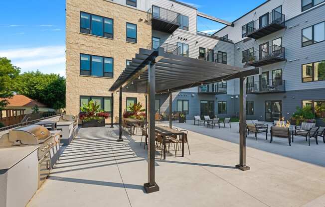 an outdoor patio with a grill and tables and chairs