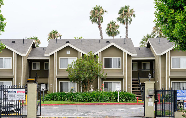 a row of apartment buildings with palm trees in the background at Sagewood Gardens Senior Apartments, California, 91745