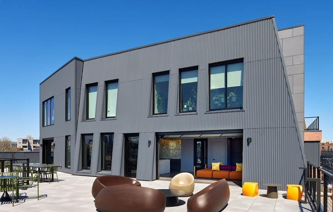 A modern building with a grey exterior and a patio with bean bag chairs.