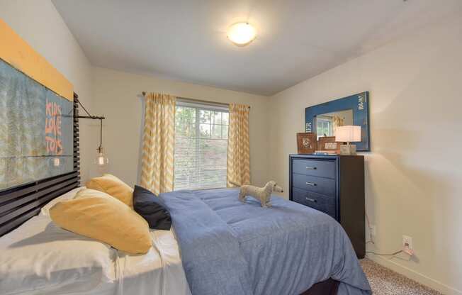 Master Bedroom with Kings Sized Mattress with Blue Comforter, Woven Dog, Black Dresser, Carpet and
