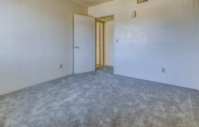 an empty bedroom with white walls and carpet