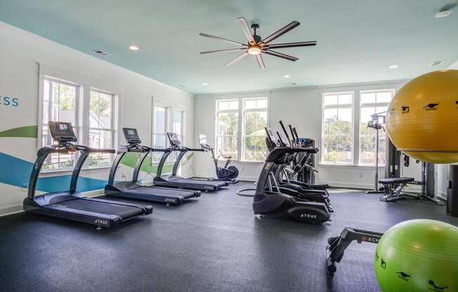 a gym with cardio equipment and a ceiling fan