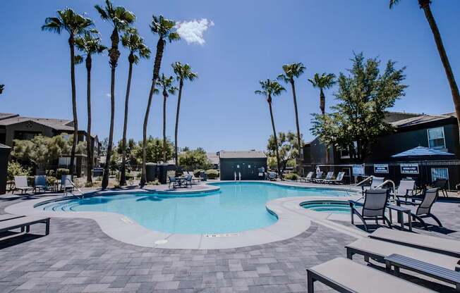 A pool surrounded by palm trees and lounge chairs.