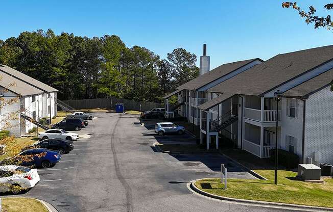 a view of a street with houses and cars in a parking lot