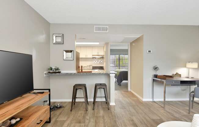 a living room with a kitchen in the background in The Oasis Daytona's model apartment