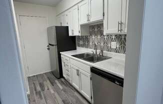 an empty kitchen with white cabinets and stainless steel appliances