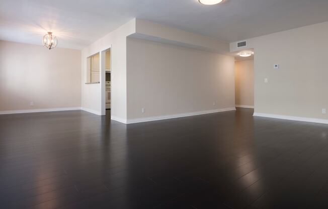 an empty living room with wood floors and white walls