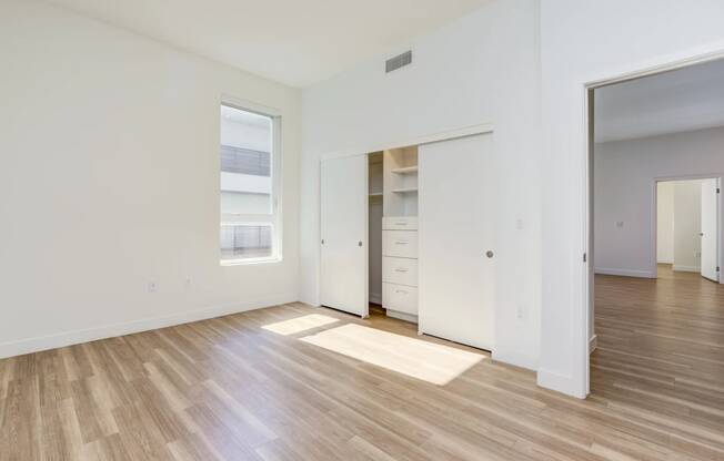 a bedroom with white walls and wood floors and a closet