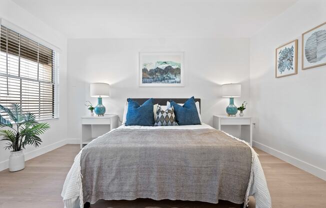 a bedroom with white walls and a bed with blue pillows