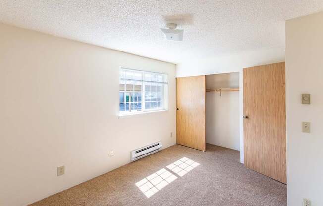 A room with a window and a carpeted floor.