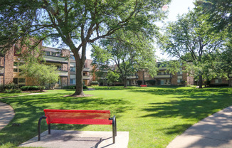 a red park bench sitting in the middle of a green park