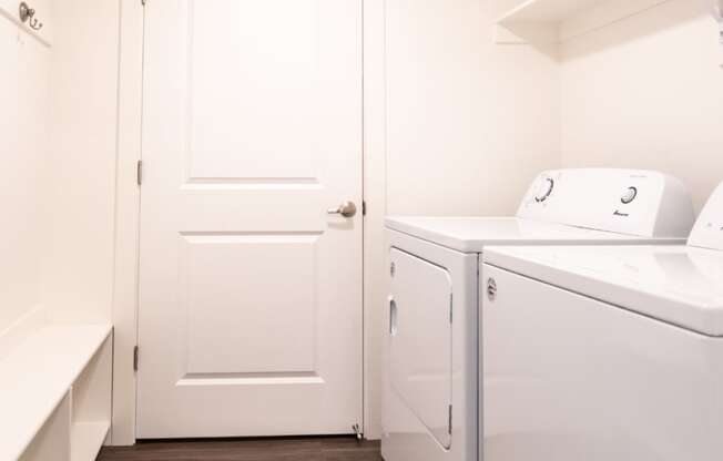 a laundry room with a washer and dryer and a white door